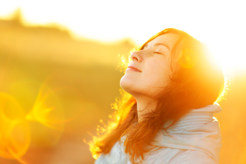 young woman similing and embracing life in field during sunset