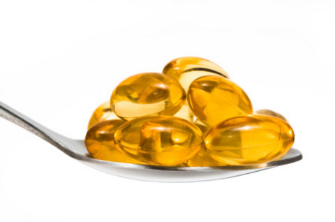 spoonful of golden colored fish oil softgels
