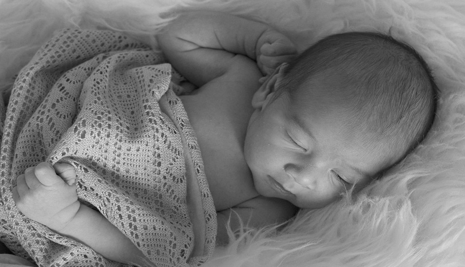 black and white image baby in blanket laying down