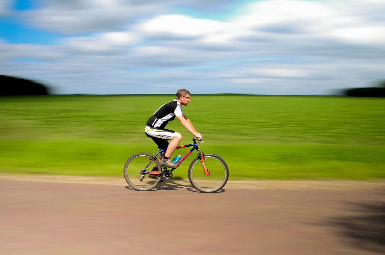 solo male cyclist with blurred grass field in background