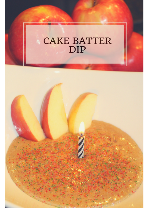 3 apple slices sitting in a cake batter dip with sprinkles, a candle, and apples in the background