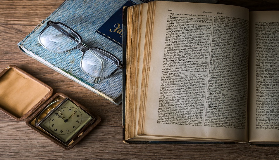 open book on top of kitchen table next to glasses and watch