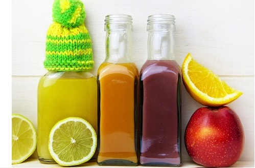 three bottles of juice next to fruit slices