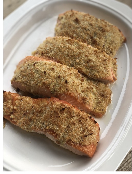 4 salmon fillets encrusted with bread crumbs atop a white plate